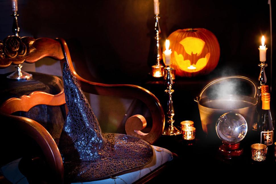 Spooky room decorated for Halloween with a witch hat, candles, a cauldron, & a Jack'o'Lantern.